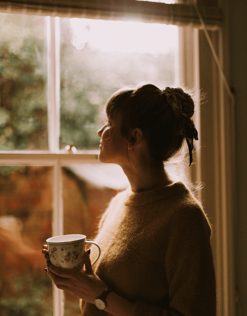 girl with a cup of coffee staring out the window